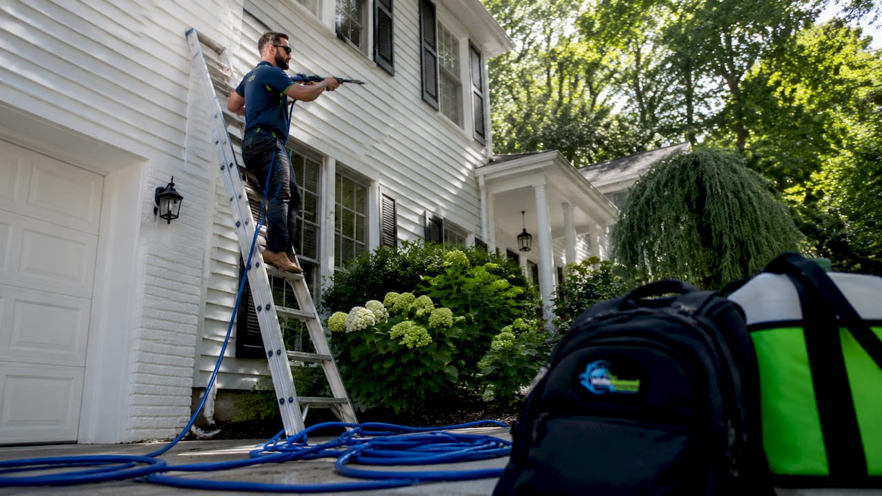 Technician soft washing home exterior siding