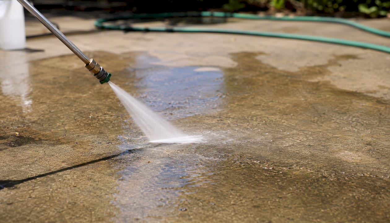 Pressure washing nozzle spraying driveway outdoors