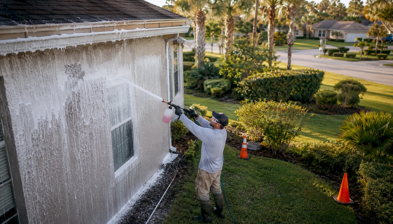 Technician soft washing house exterior