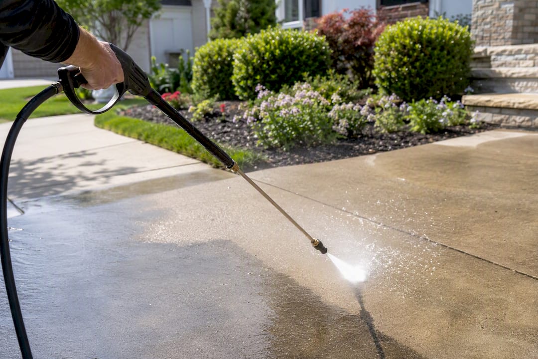 Technician pressure washing concrete driveway