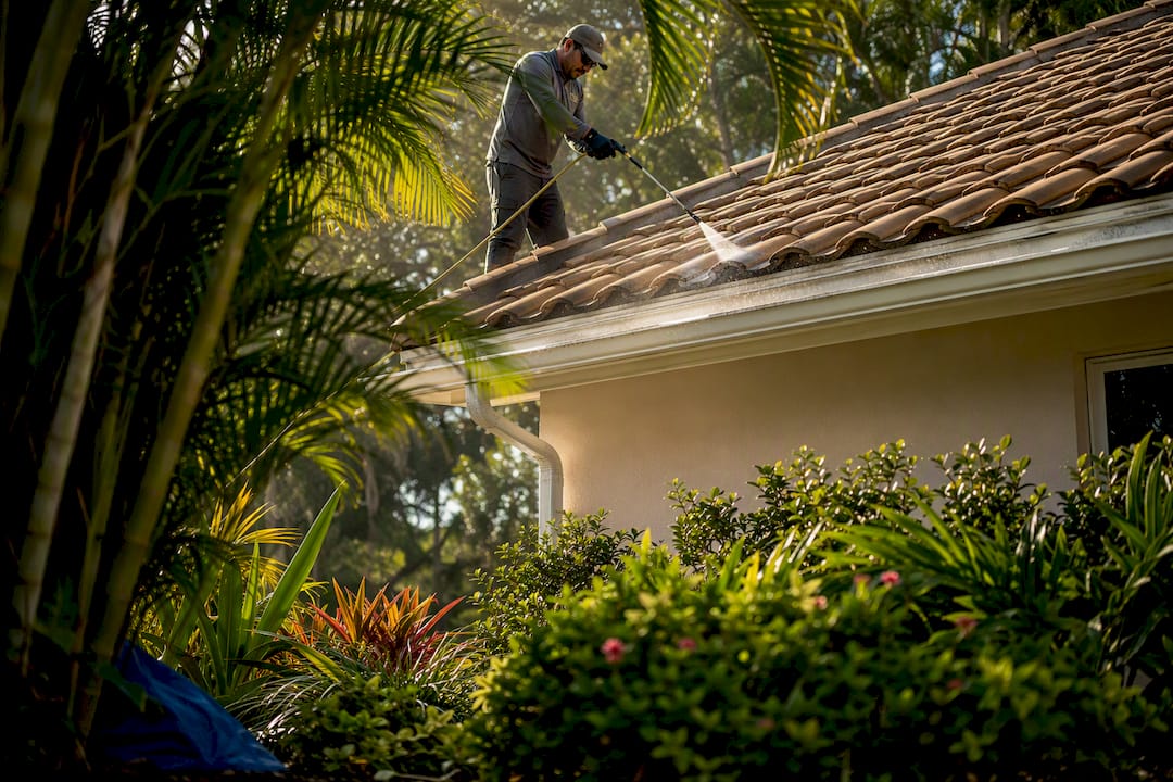 Technician safely applying roof cleaning solution