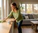 Woman cleaning window ledge in bright living room
