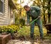 Landscaper clearing leaves near house foundation