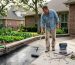 Homeowner applying sealer to concrete driveway