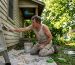 Homeowner scrubbing house siding for paint prep