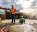 Worker cleaning outdoor walkway with changing weather
