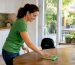 Woman wiping kitchen countertop in morning light