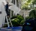 Technician soft washing home exterior siding